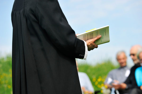 Friluftsgudstjeneste præst holder en bog